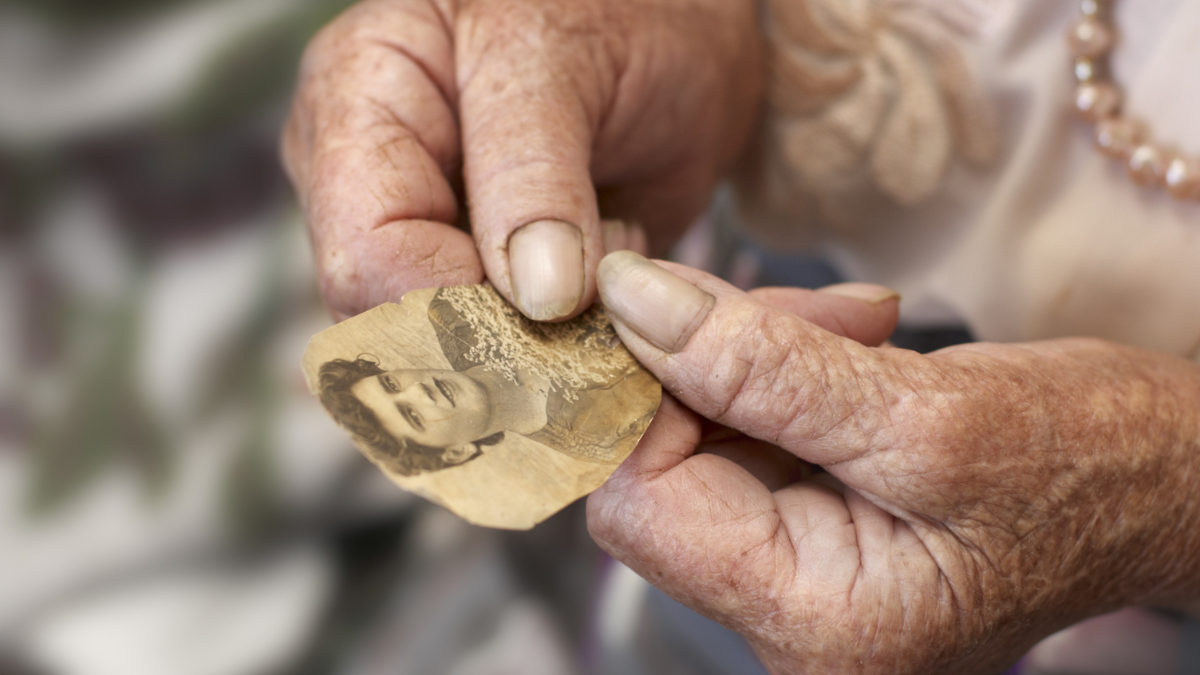 Old woman holding own photo in age of twenty.