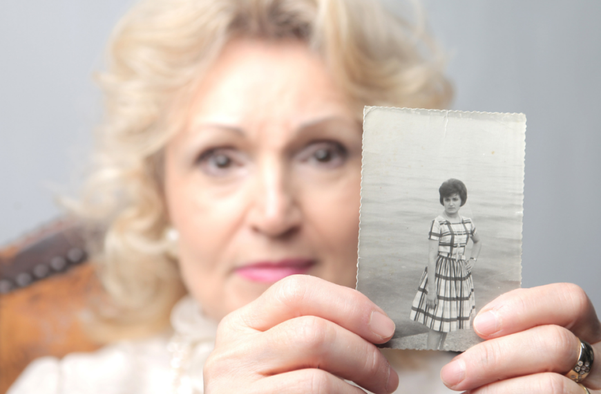 Senior woman showing an old photograph of herself.