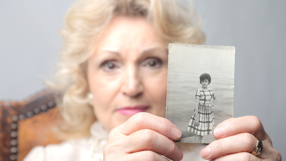 Senior woman showing an old photograph of herself.