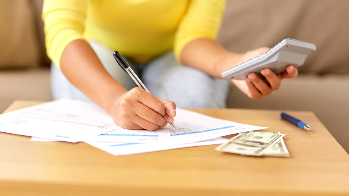 business, finances and people concept - woman with money, papers and calculator at home.