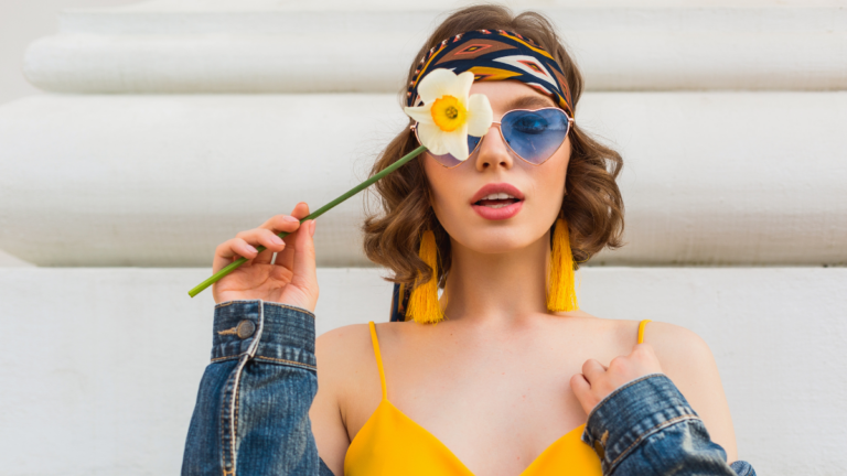 beautiful sexy woman in yellow stylish dress wearing denim jacket, holding flower, trendy outfit, hippie indie style, spring summer fashion trend, blue sunglasses, street fashion, trendy accessories.