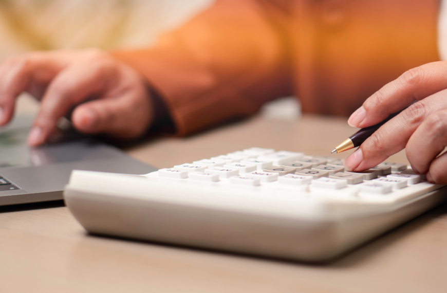 Financial accounting and business budgeting concept. Professional calculating business expenses with calculator and laptop, illustrating finance management, audit, and economic planning.