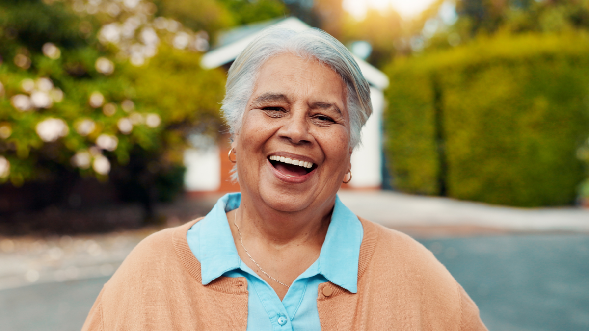 Portrait, outdoor and senior woman at retirement home with laughing, happiness and relax on weekend. Smile, funny and face of elderly female person from Mexico in backyard of nursing facility.