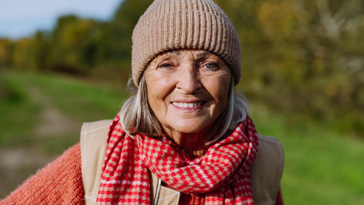 Portrait of beautiful older woman with a gray hair. Female senior standing outdoors in nature, looking at camera and smiling.