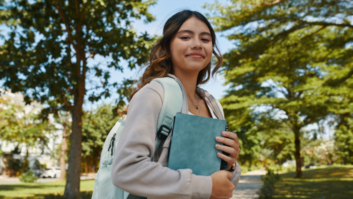 Portrait of smiling schoolgirl with students books in hands.