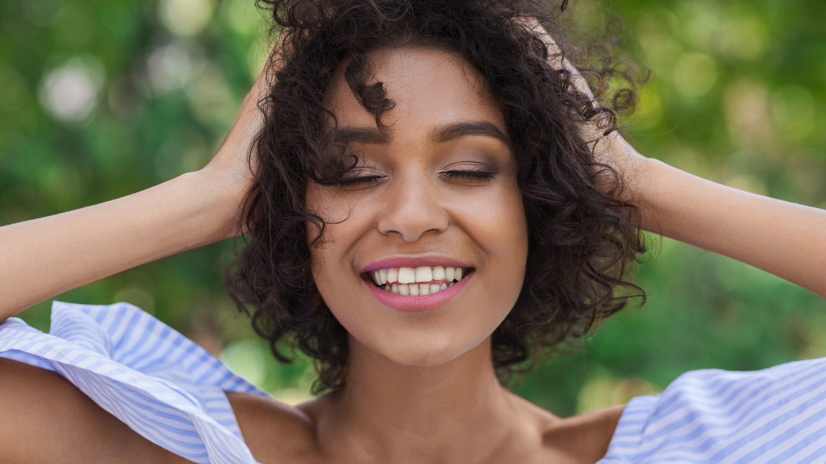 Excited african-american woman having rest and feeling happy outdoors in the park.