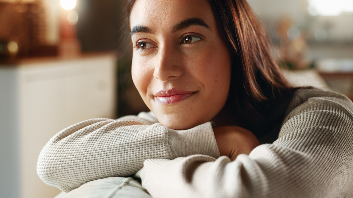 Face, memories and smile with woman on sofa in living room of home for contemplation or wellness. Future, idea and thinking with happy person in apartment for nostalgia, vision or weekend planning.