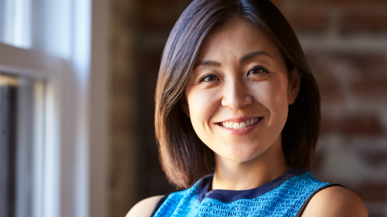 Portrait Of Businesswoman In Office Standing By Window.