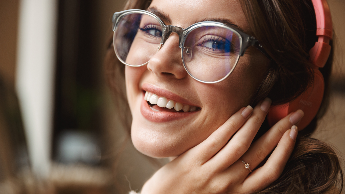 Image of young beautiful caucasian woman wearing headphones smiling and listening to music in cafe.
