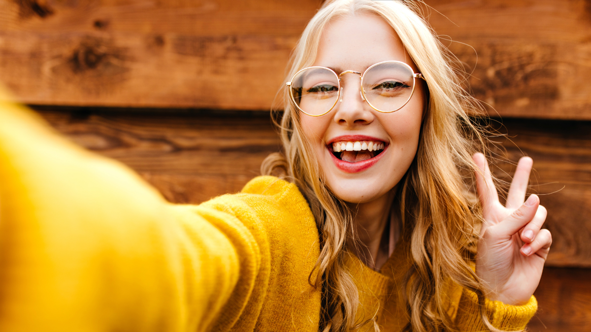 young attractive cheerful girl takes a selfie and makes peace sign with her fingers.