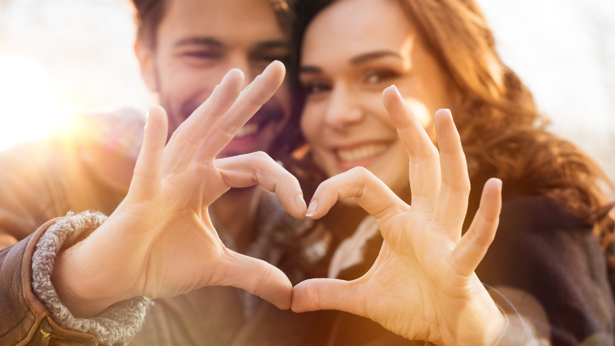 Closeup of couple making heart shape with hands having romantic date night.