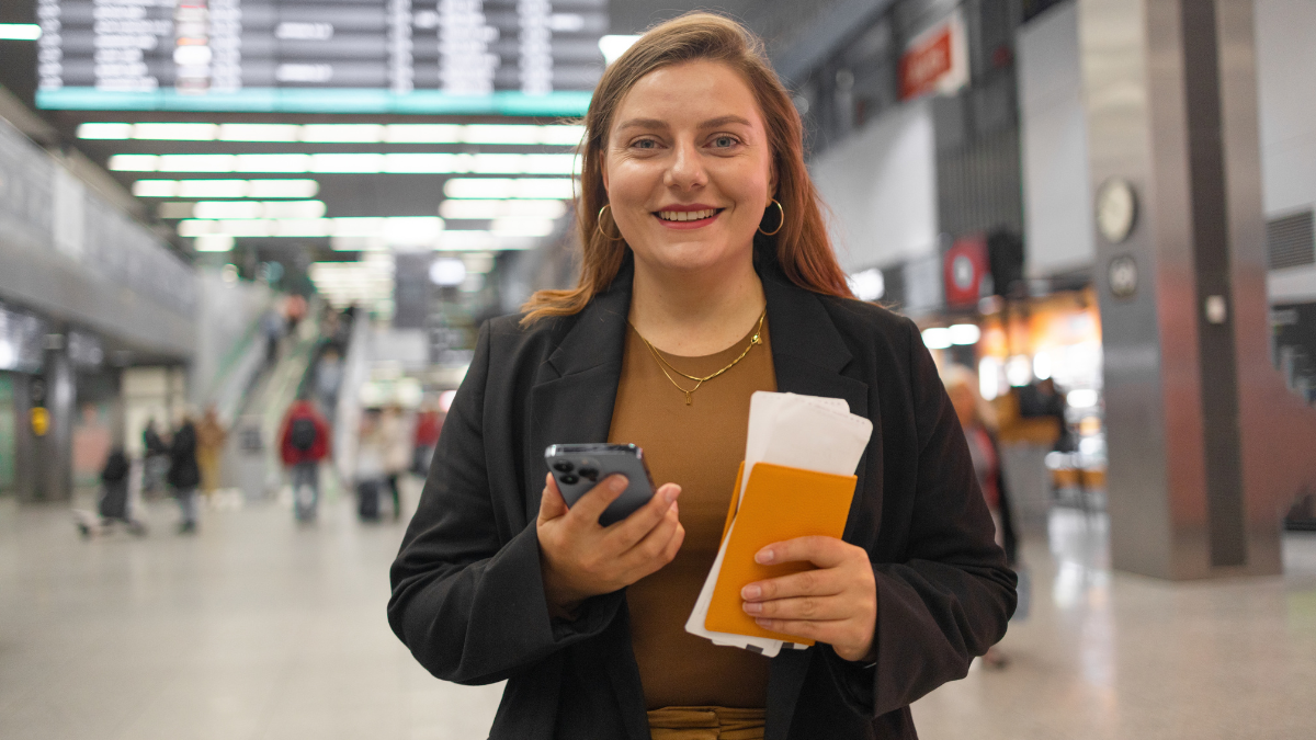 How To Save Money on Holiday Travel: Smart Tips for Budget-Friendly Trips 1 Portrait of Caucasian traveler woman hold ticket ready enjoy voyage tour passenger walk in airport terminal to boarding gate. Attractive beautiful female tourist excited to go travel abroad by.