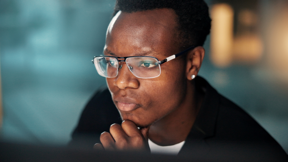 Night, thinking or businessman reading with laptop, tech or news for research or funding solution. Problem solving, auditor or African financial advisor in office for accounting deadline or overtime.