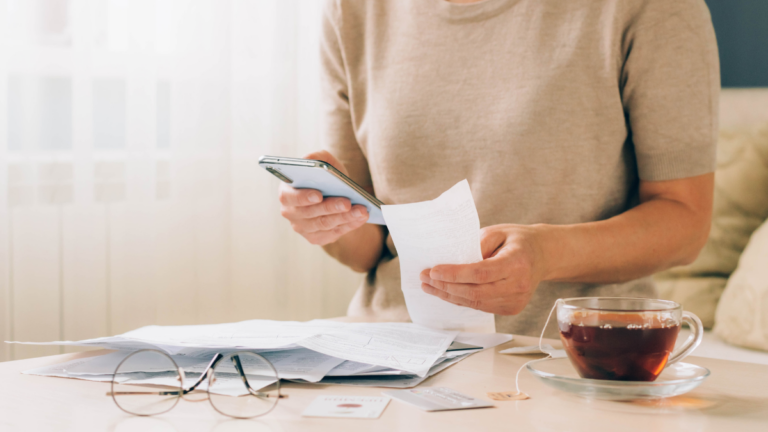Woman holds phone in her hands for paying bills, receipts of financial checks, budget planning, tracking spending.
