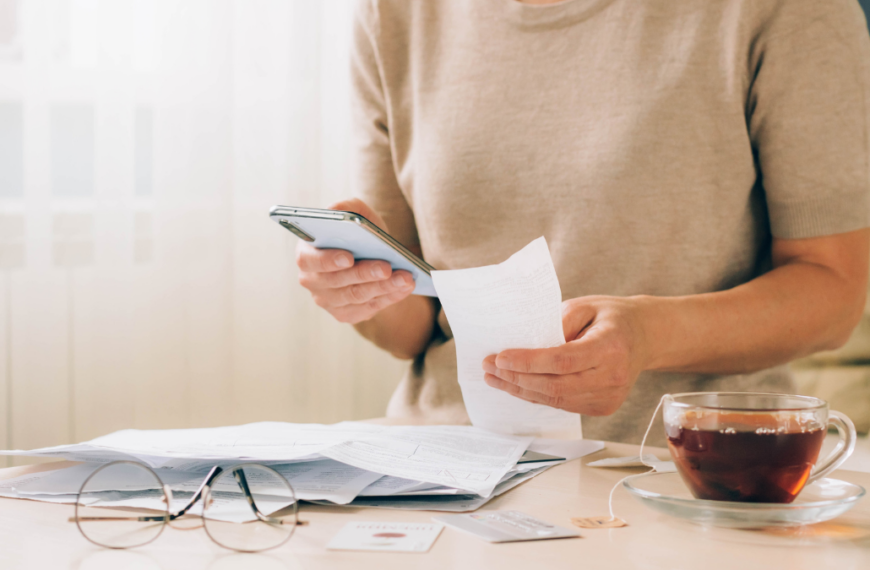 Woman holds phone in her hands for paying bills, receipts of financial checks, budget planning, tracking spending.
