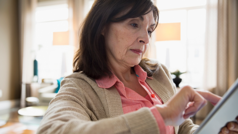 Woman using digital tablet in living room.