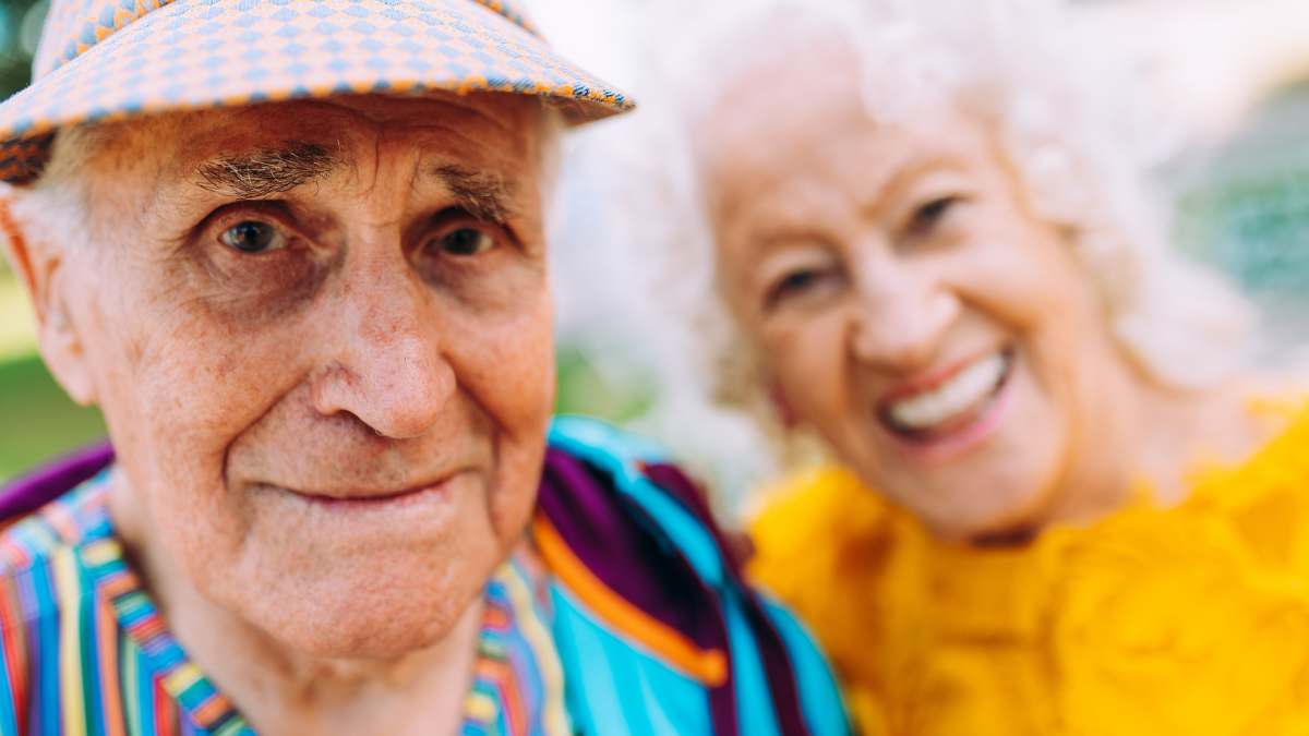 Old modern couple dressing fashionable colored clothes. Youthful grandmother and grandfather having fun outdoor and going wild. Representation of elderly people feeling young inside.