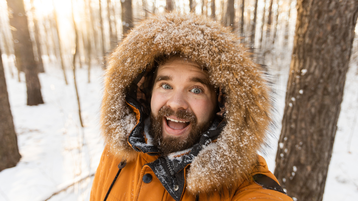 Excited man enjoying winter forest walk and taking selfie. Joy, freedom and connection with nature during the snowy season.