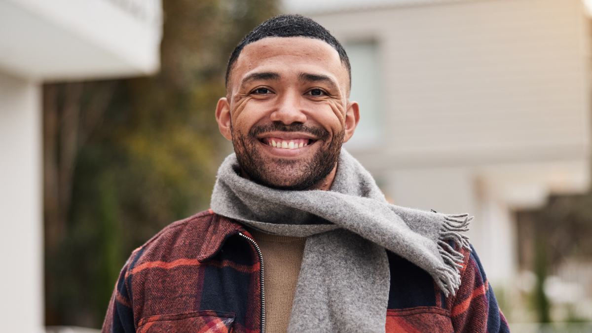 Outdoor portrait, man and fashion for winter with style inspiration, organic fabric and cotton scarf in home. Male person, happy smile and warm clothes for cold climate, ethical brand and wellness.