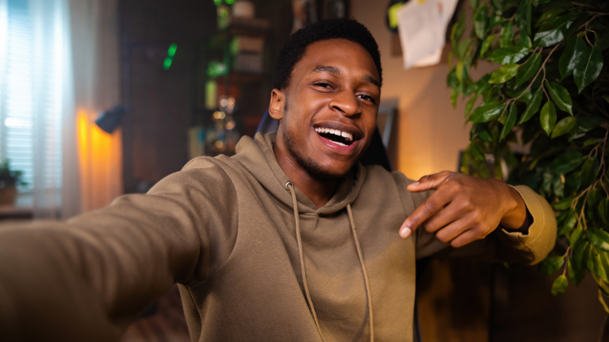 Dark skinned African American man raises his fists in victory, i indicating that he made money in a side hustle for teens.