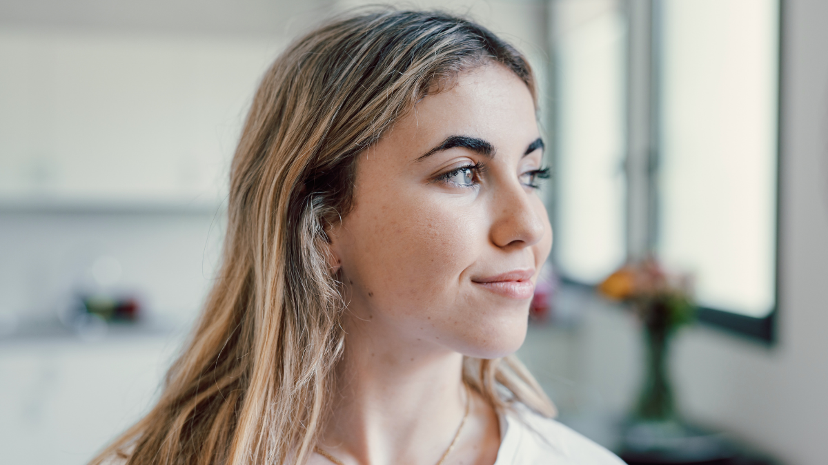 Head shot close up dreamy young smiling beautiful woman looking away, visualizing future indoors of recollecting good memories. Happy healthy millennial girl enjoying free weekend time at home.