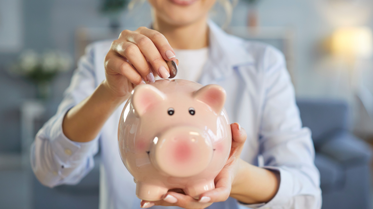 Unknown woman holding biggybank, putting coins, saving money for purchasing something desirable, going to spend her savings soon, recommending finance collecting. Financial stability concept.