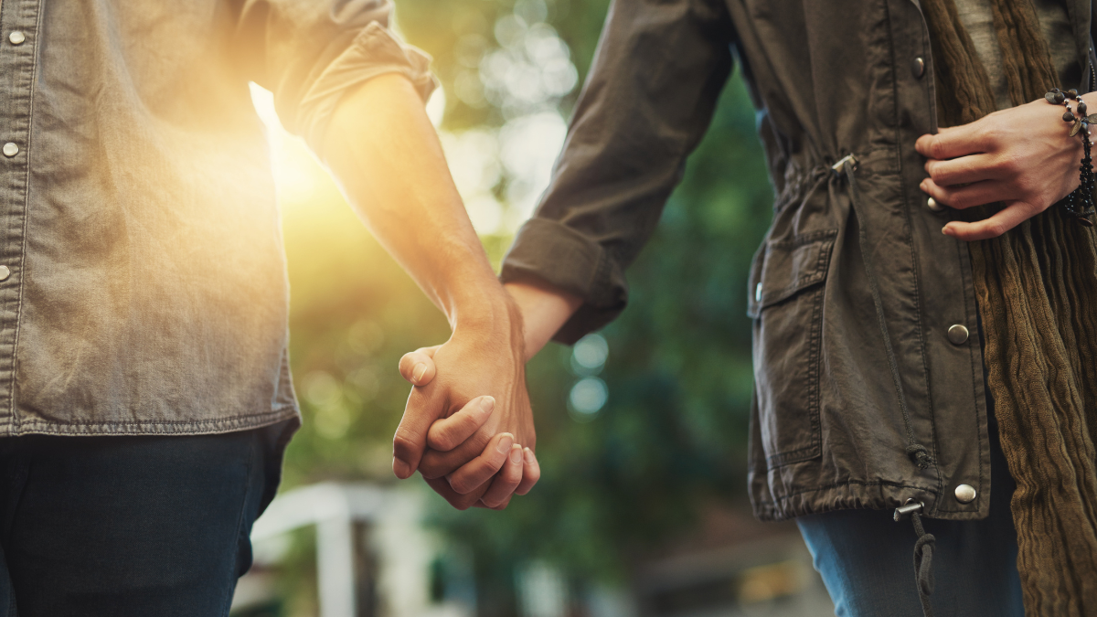 Love, holding hands and couple in city for travel, journey and bonding outdoor with fun, freedom or adventure at sunset. Lens flare, trust and people outside for urban shopping, experience or date
