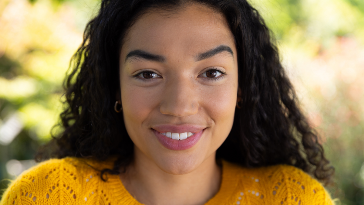 Portrait of happy biracial woman in yellow sweater in sunny nature. Lifestyle and domestic life, unaltered.