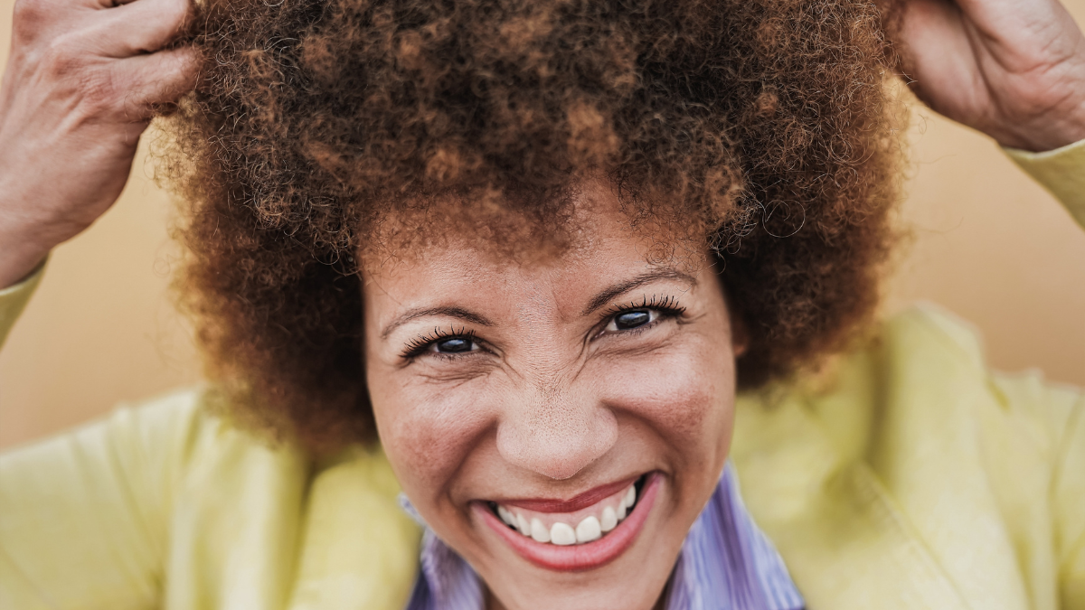 Happy mature latin woman with afro hair smiling on camera - Joyful elderly person and healthy lifestyle concept of frugal swaps.