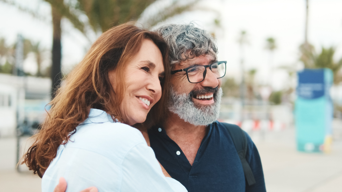 Close-up of an elderly couple standing on the embankment and looking into the distance with smile.