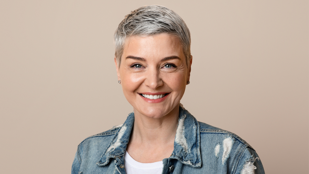 Portrait Of Beautiful Stylish Mature Woman With Short Hair Smiling At Camera While Posing Over Yellow Studio Background, frugal living tips.