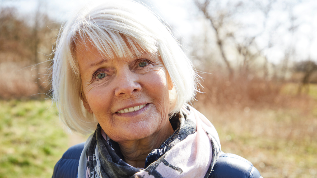 Smiling senior woman in scarf for proven frugal living tips.