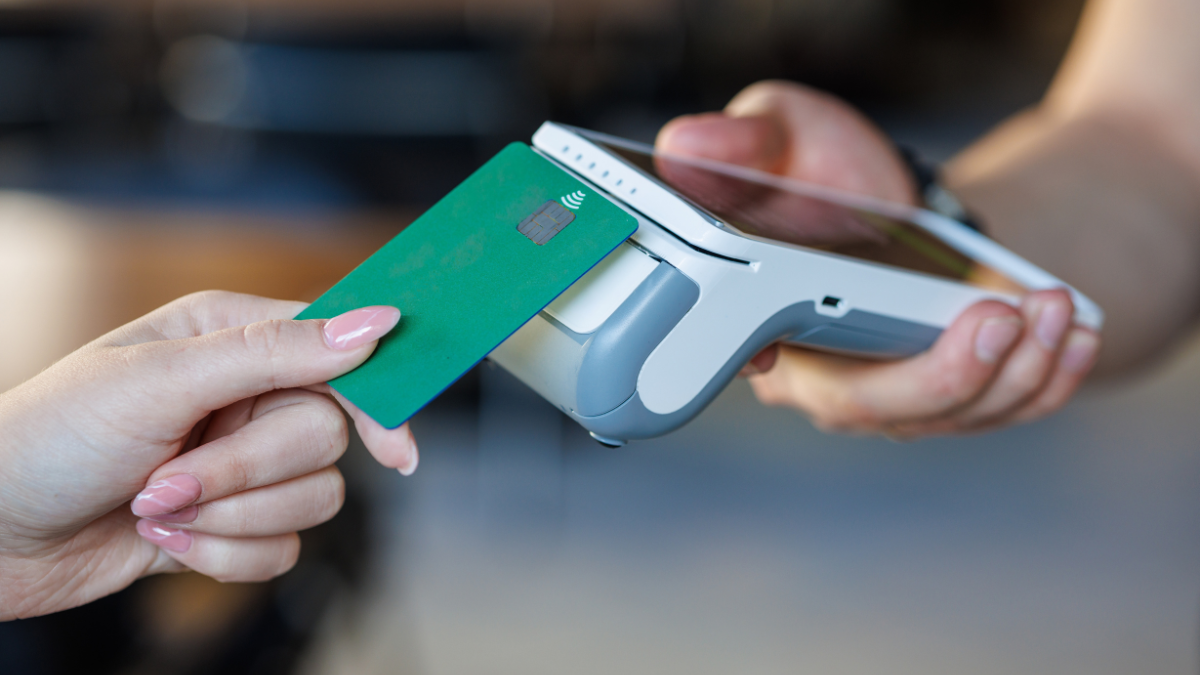 Closeup of a bank card tapping a wireless POS for secure cashless checkout, ideal for fintech, retail, SMB, and payment tech marketing.