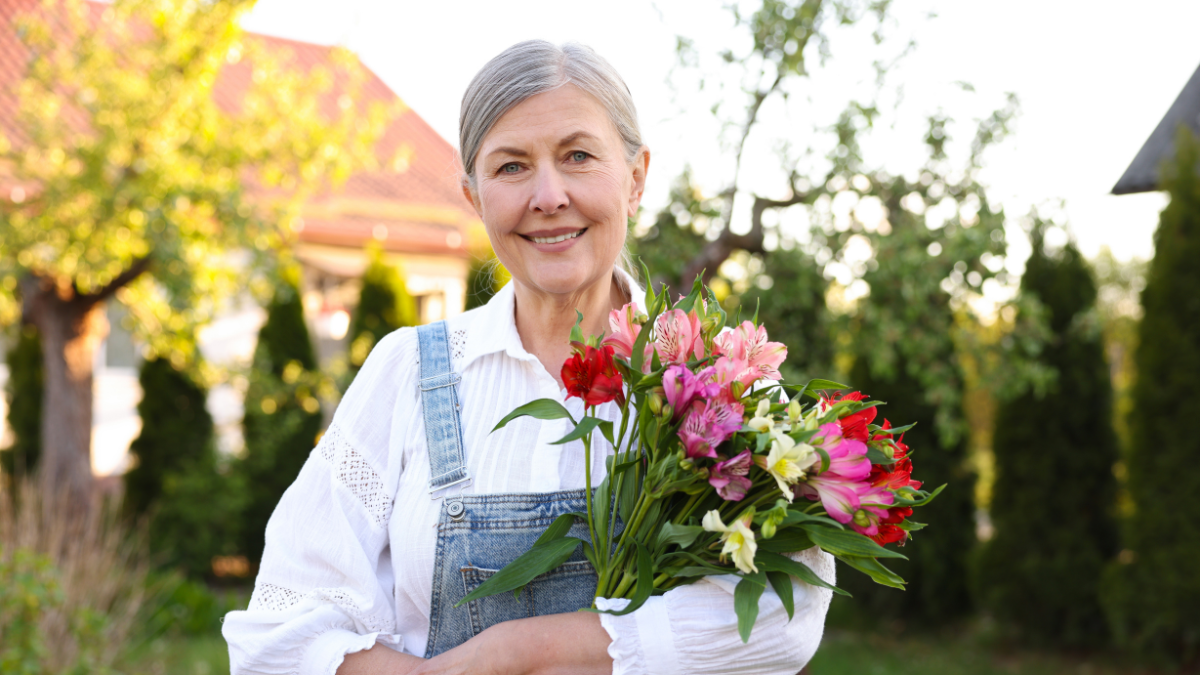 Senior woman with beautiful flowers outdoors. Gardening season "Outdated" Frugal Living Tips Frugal People Are Quietly Bringing Back.