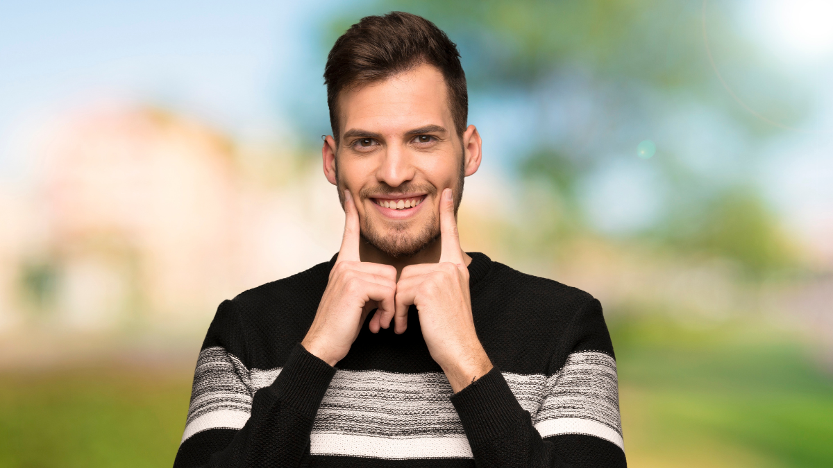 Handsome man smiling with a happy and pleasant expression at outdoors.