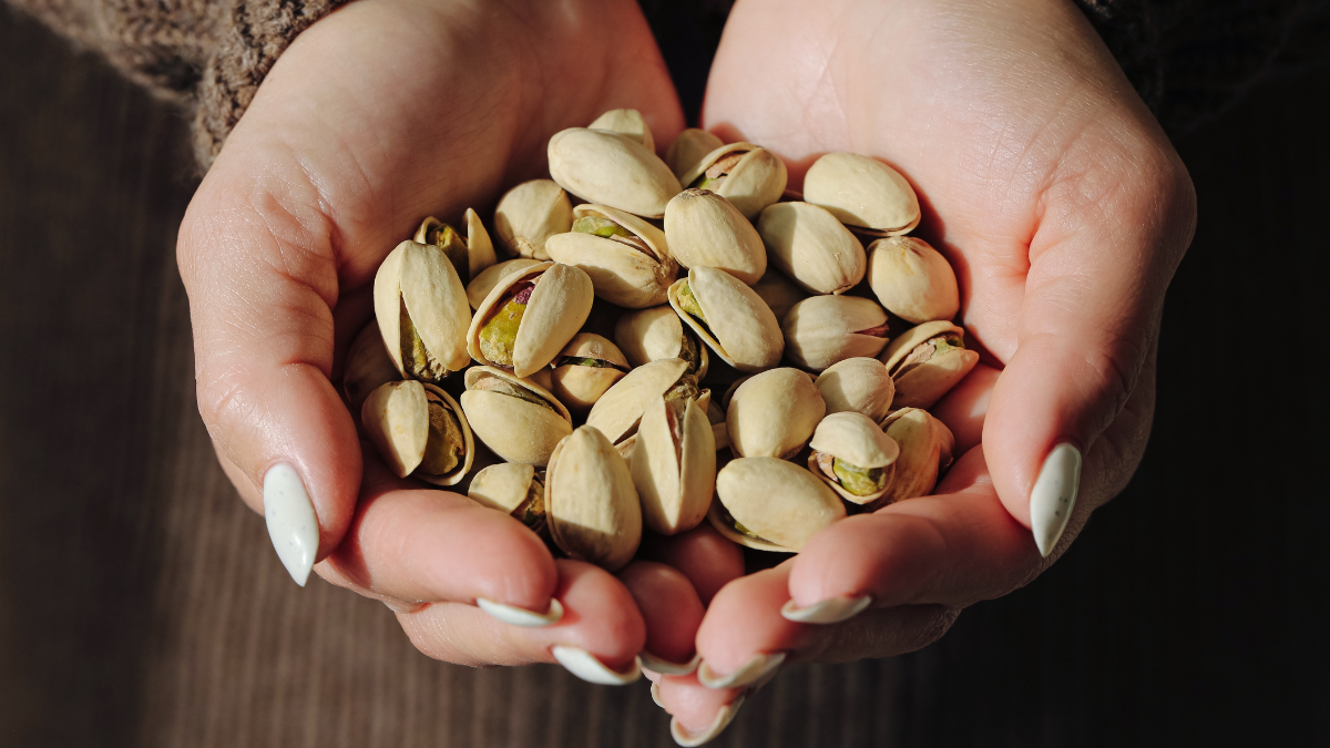 Woman holding pistachio nuts in hands close up. Healthy snack and natural protein source. Roasted shell pistachios for vegetarian diet and everyday nutrition concept indoors daily How To Eat More Protein.