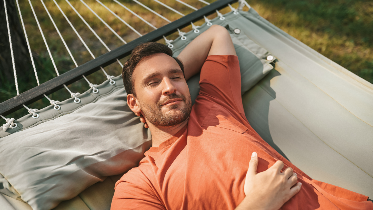 Man napping in hammock in nature.