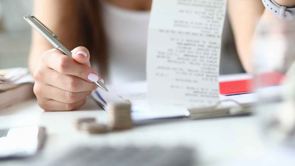 Woman hold silver pen and check in hand. Home budget concept. Wife checks a notes and brings balance Budget Challenge: Are You Ready?.