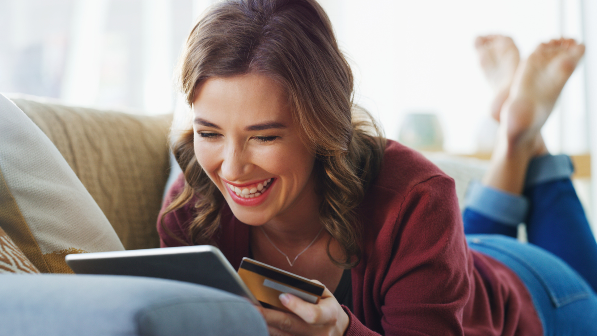 Smile, debit card and woman with tablet in living room for relax, payment or online shopping. Tech, credit score and happy person in home for internet banking with investment, savings and ecommerce How To Clean Up Your Credit.