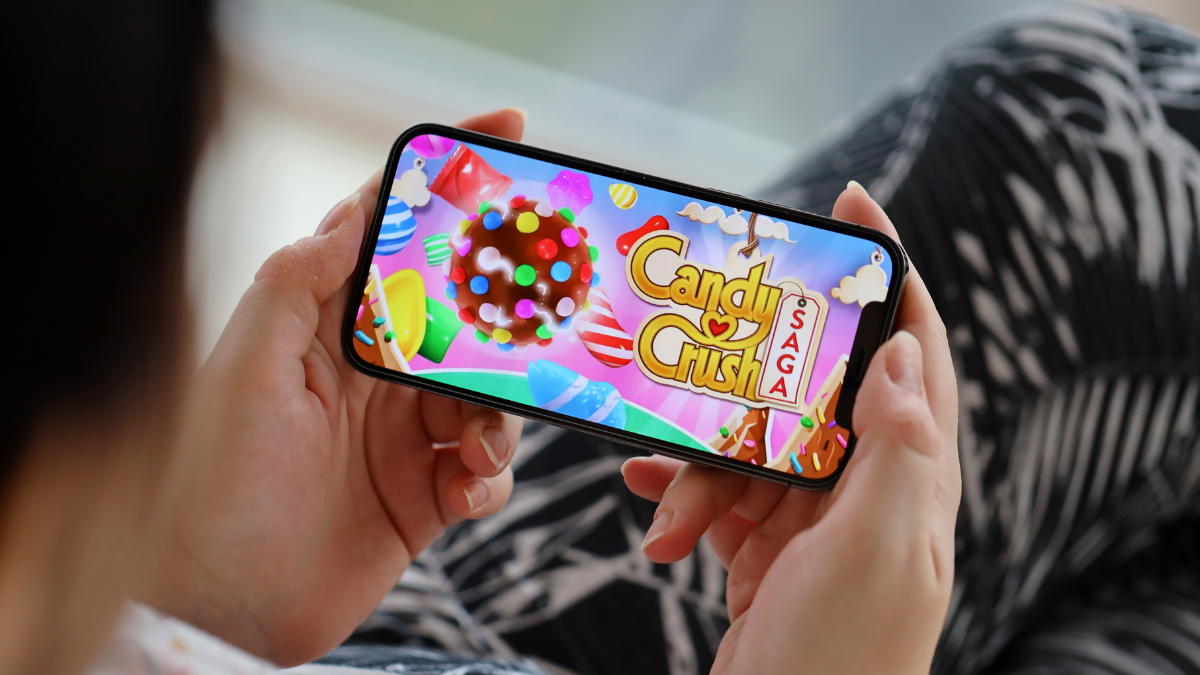 Candy Crush Saga mobile iOS game on iPhone 15 smartphone screen in female hands during mobile gameplay. Mobile gaming and entertainment on portable device.