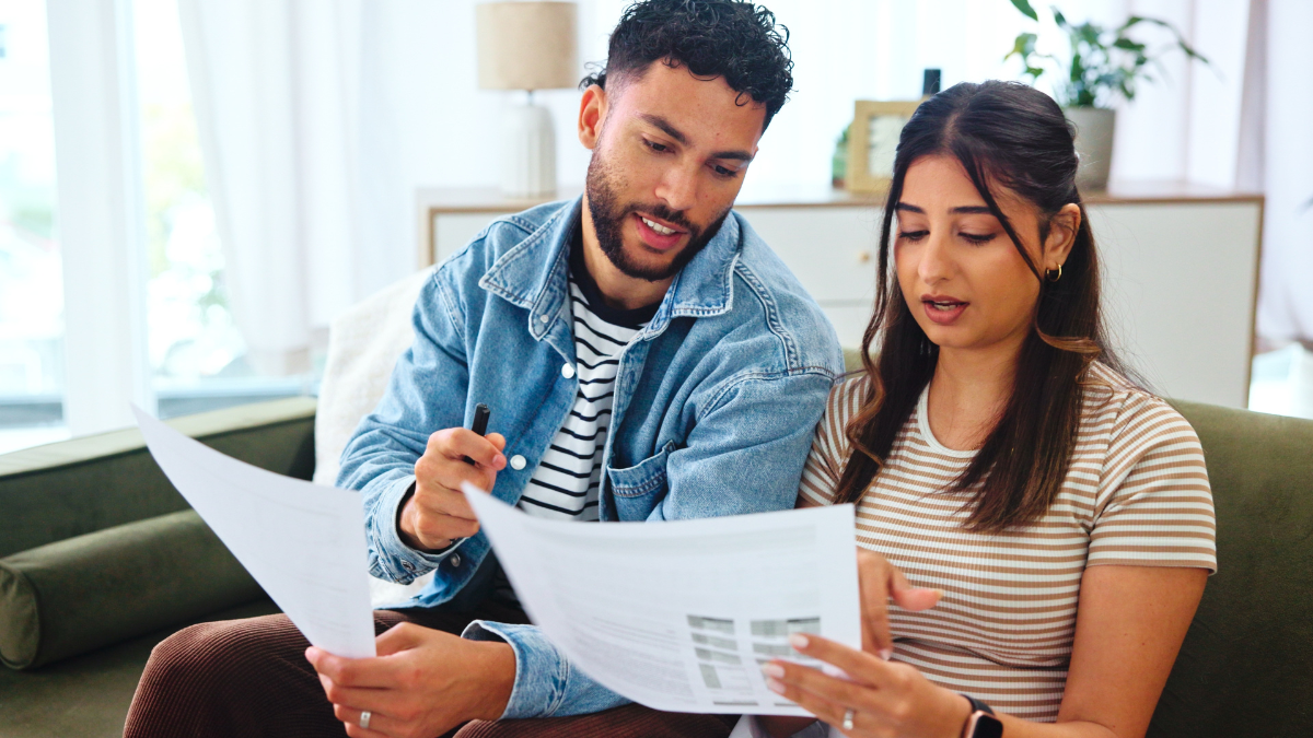Documents, taxes and couple on sofa in home for bills, payment receipts and banking. Marriage, relationship and man and woman with paperwork for financial planning with mortgage, insurance and budget. Four Walls of Budgeting.