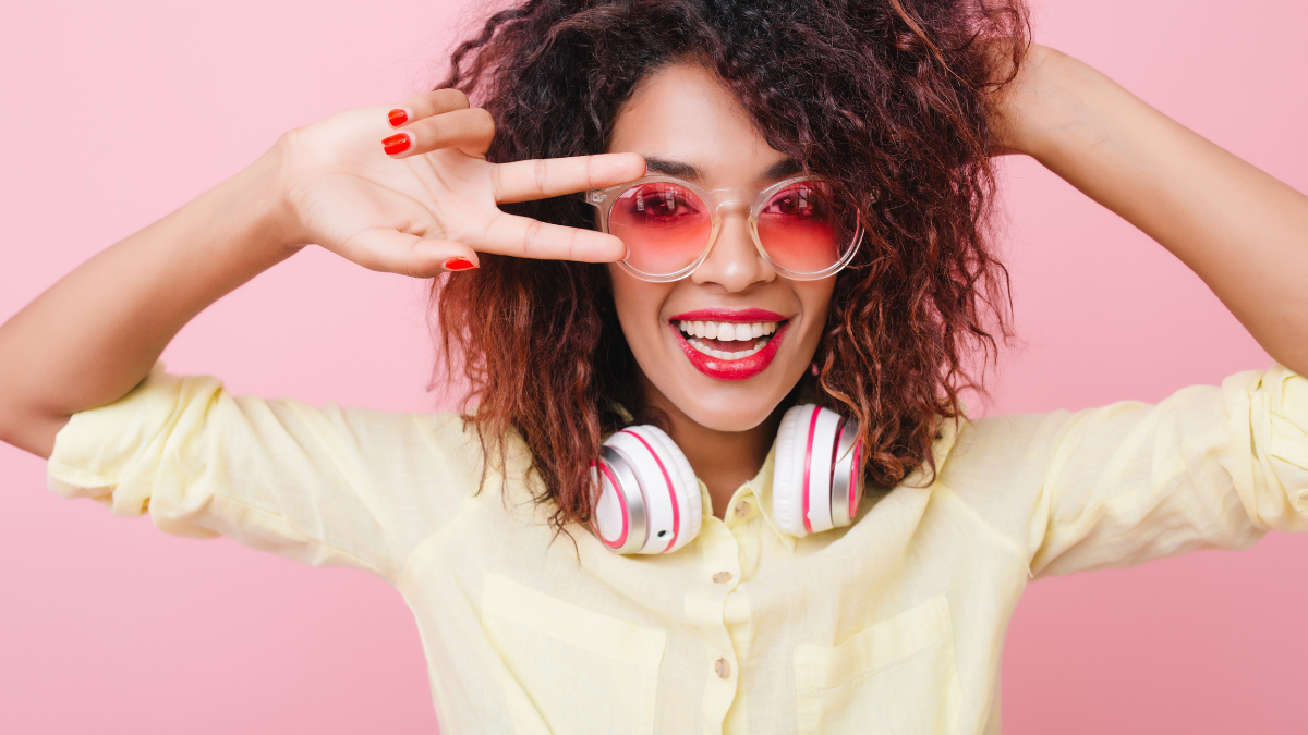 Inspired young woman with african hairstyle expressing positive emotions during romantic indoor photoshoot. Gorgeous dark-haired lady in vintage sunglasses having fun alone. things to do at home alone.