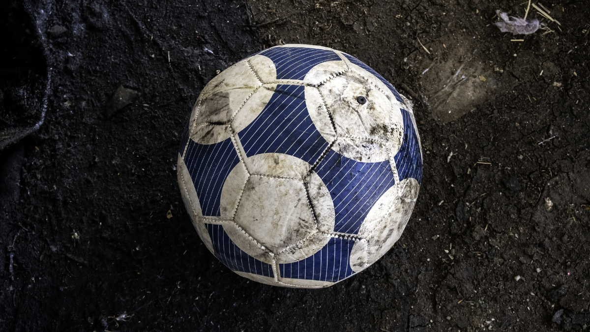 Old soccer ball lying on the street, sport and exercise.