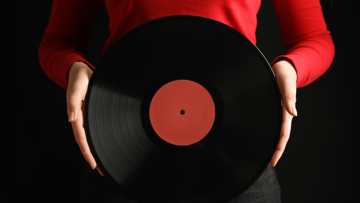 Woman with vintage vinyl record on black background, closeup.